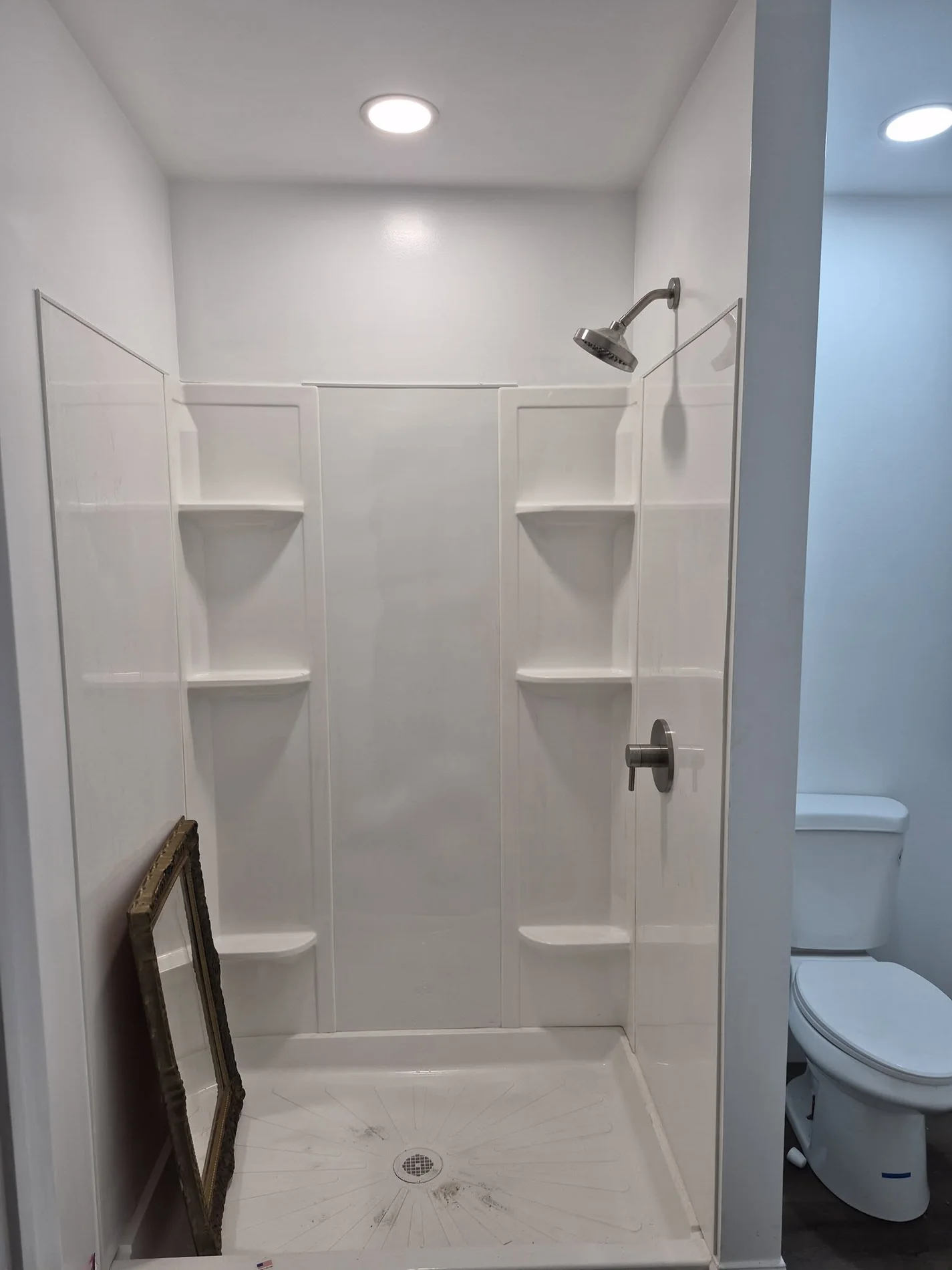 Bright shower-area improvement with built-in shelving and updated fixtures.